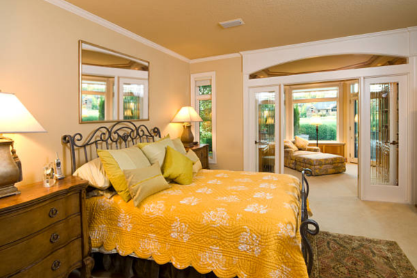 Black wrought iron bed frame with yellow blanket in a bedroom.