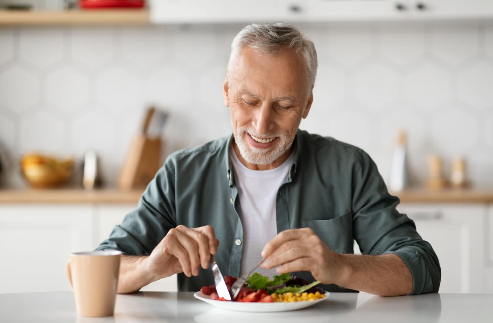 A happy older adult man enjoying a delicious meal.