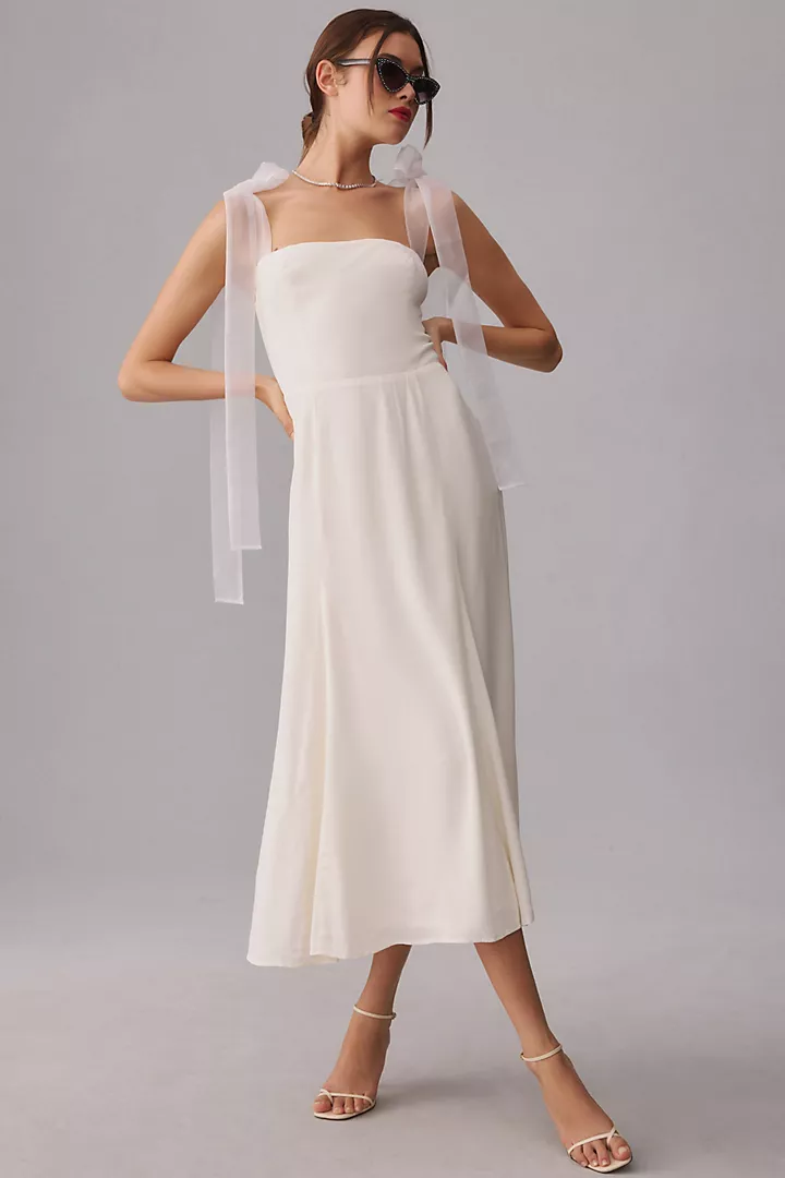 Introducing the Kairo: an airy and elegant midi A-line dress with a fitted silhouette, boasting a straight neckline and a smocked back bodice for a tailored fit. This dress showcases organza tie straps, allowing for customizable adjustments. For optimal fit, we recommend sizing down. Crafted from viscose and rayon, this dress remains unlined, ensuring comfort. Its midi-length A-line silhouette is accentuated by an invisible back zipper for a seamless appearance. Designed with tie straps, a straight neckline, and a fitted smocked-back bodice, this dress exudes effortless style. Dry clean recommended. Made in the USA.