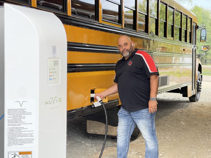 Martinsville ISD Principal Keith Kimbrough pictured with a Blue Bird Vision electric bus, and Nuvve Level 2 charger.