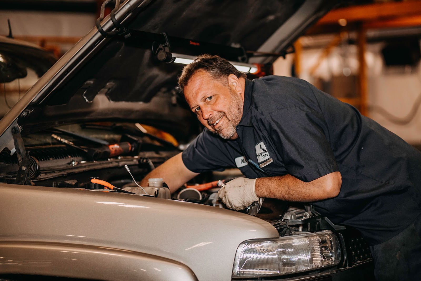 An Equipment Experts employee smiling at the camera while working on the inside of a Ford pickup truck