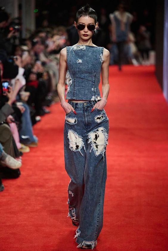 Picture showing a model on a runway rocking a distressed denim with the boots 