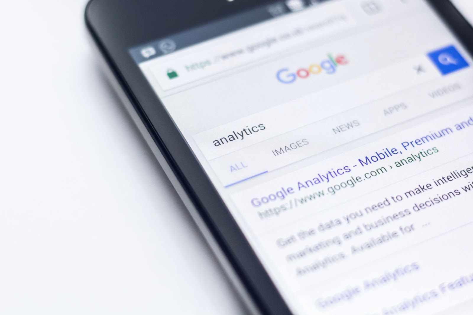 Smartphone's screen showing Google's search bar with 'analytics' in the search bar