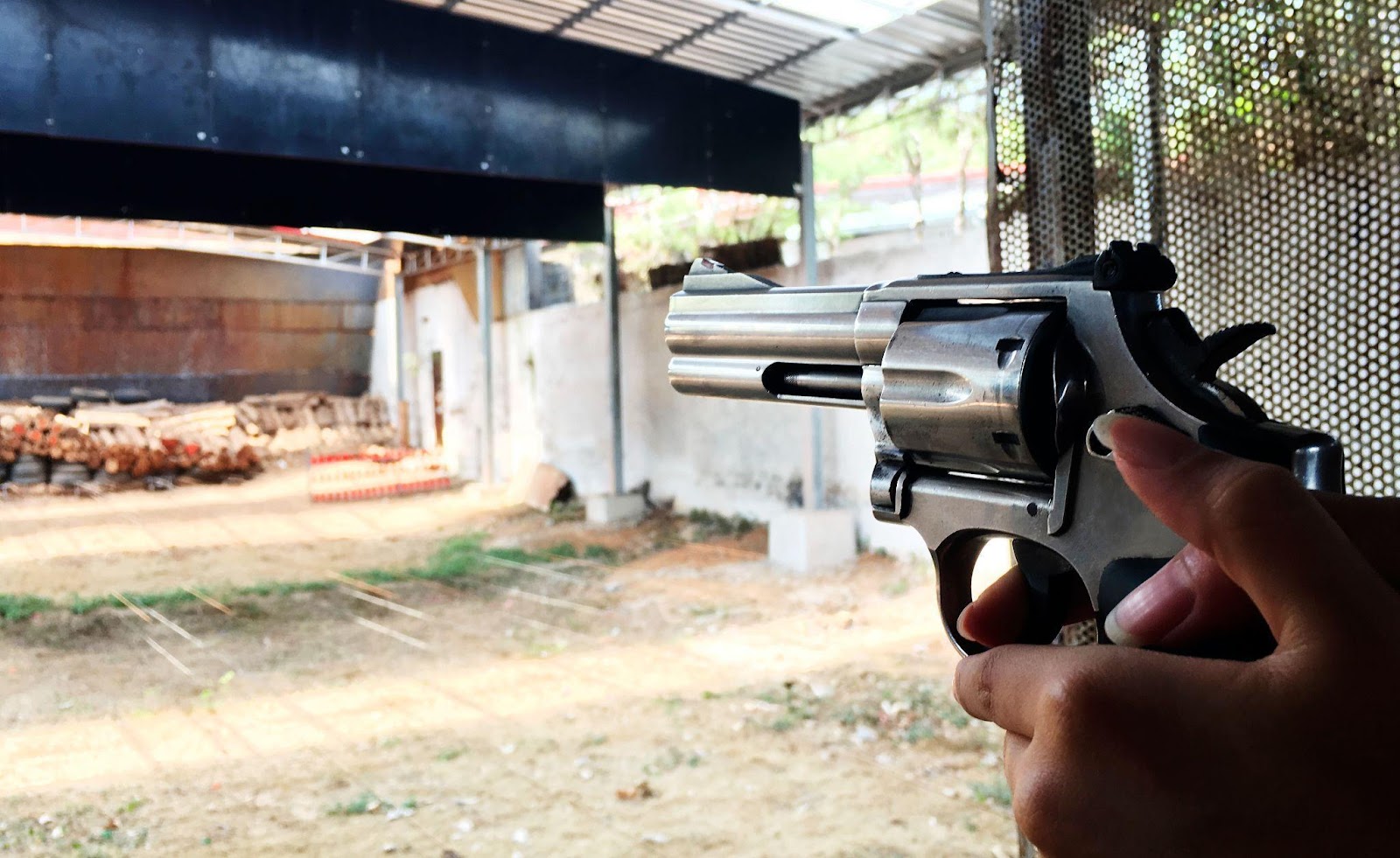 ženské ruce držící revolver míří do prostoru střelnice