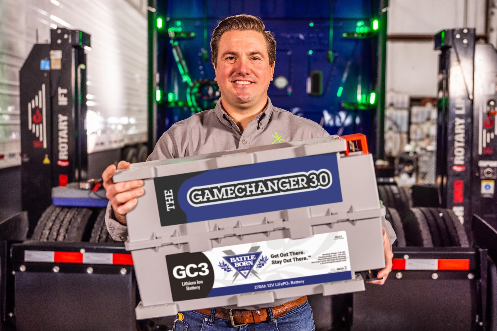 Trucking expert, DJ Hasler standing in front of a semi truck smiling and holding a Battle Born GC3 battery.