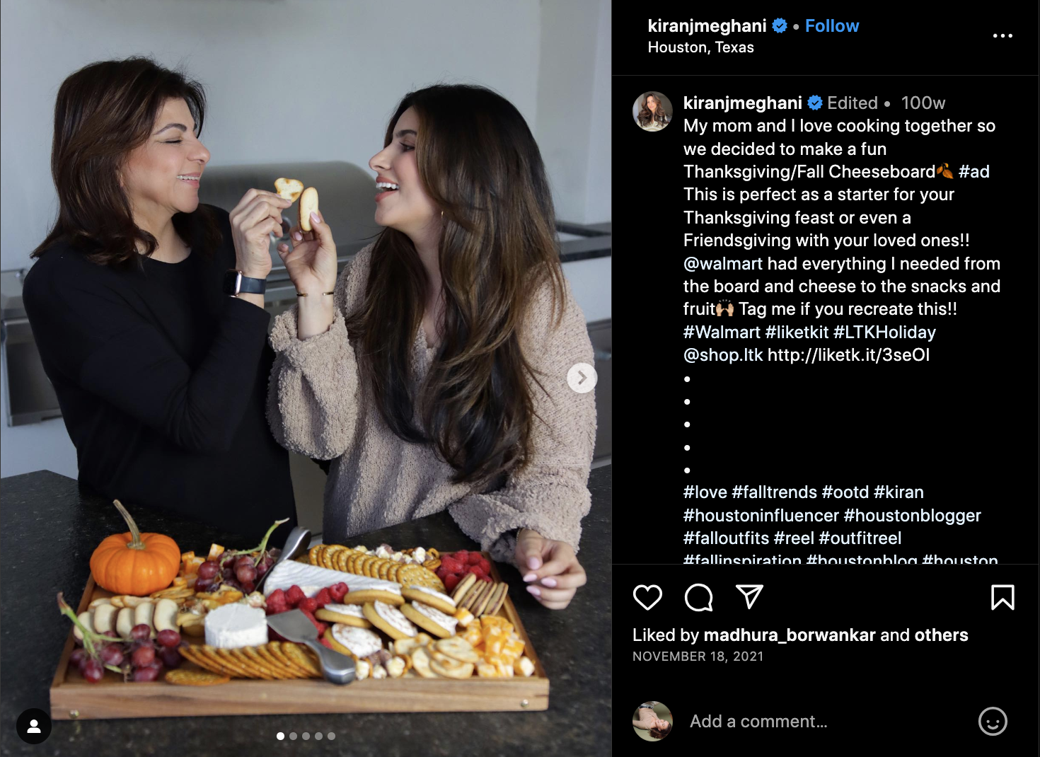 Mother and daughter influencers cheersing crackers as they stand behind their Thanksgiving cheese board