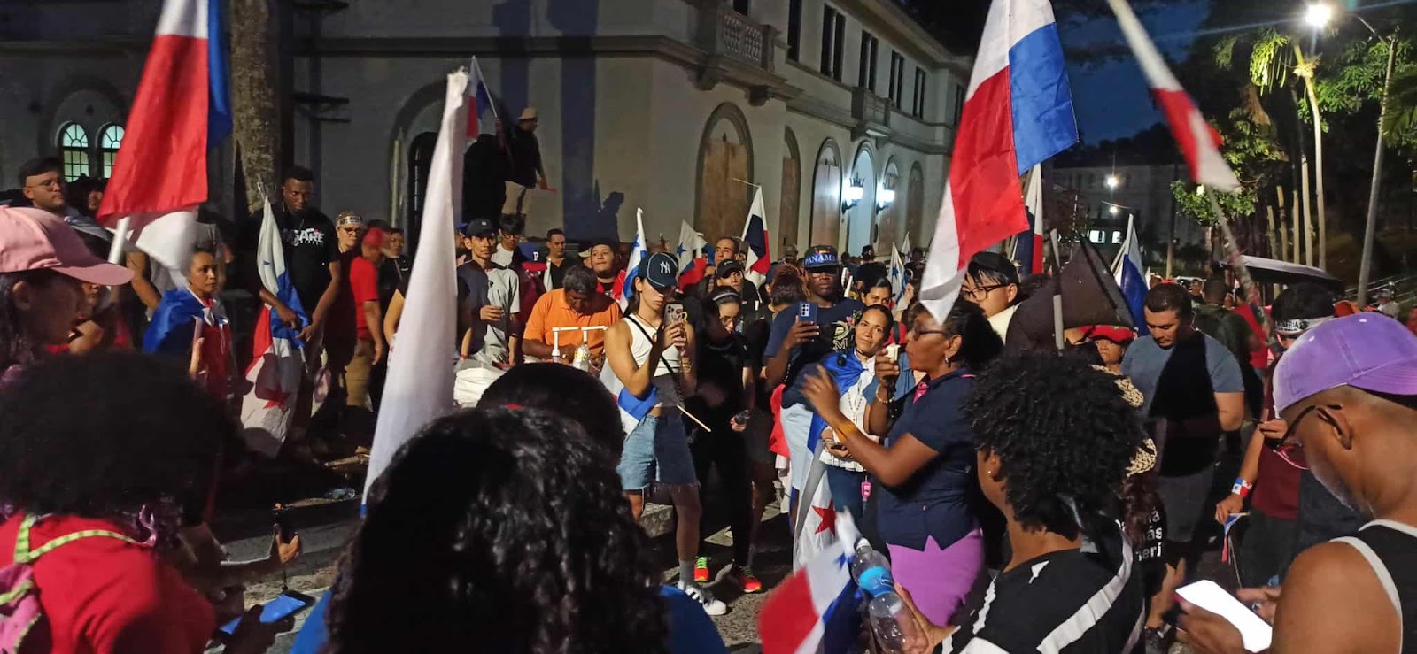 A woman speaks to a crowd of protesters during a night time rally outsdie the supreme court.