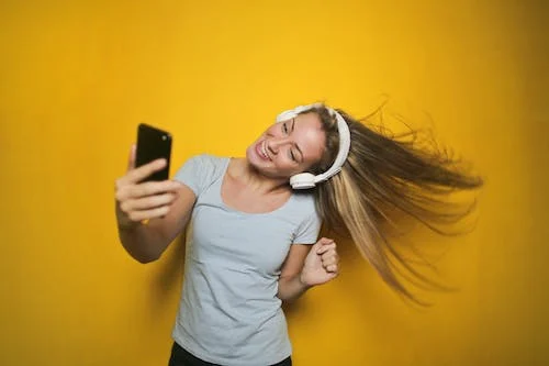 Girl is Taking a Selfie in Cherishing Mood with Hair in Air and Listening to Music