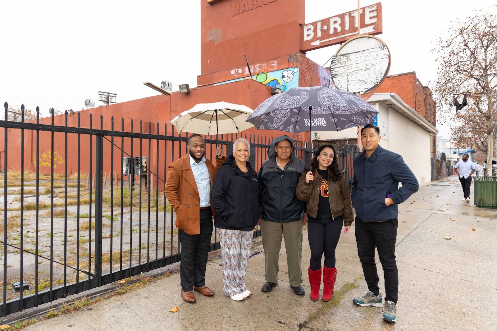 Mentors and students hold umbrellas and smile in a group picture