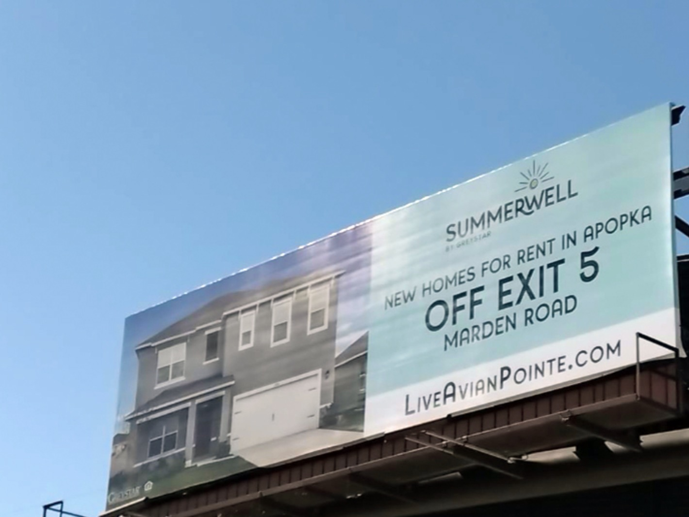 A real estate outdoor ad depicting a home next to the business name, website, and directions.