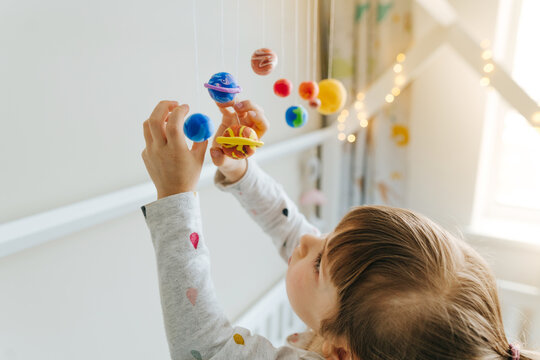 Little girl playing with toy planets made by herself from colorful molding clay indoor - Image of Ge