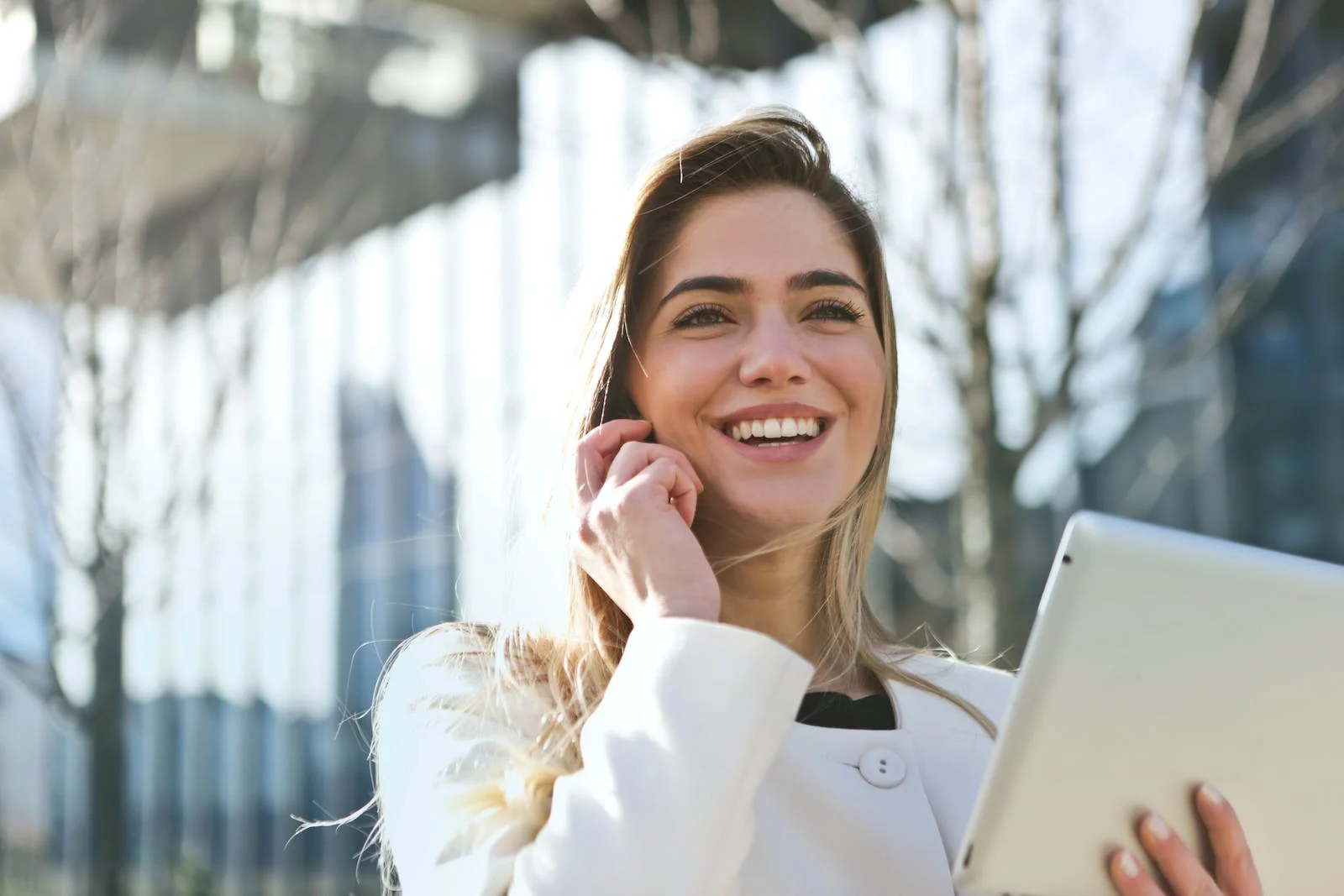 This is a picture of a blonde white woman talking on a cellphone and holding a tablet. (source https://www.pexels.com/search/career/)