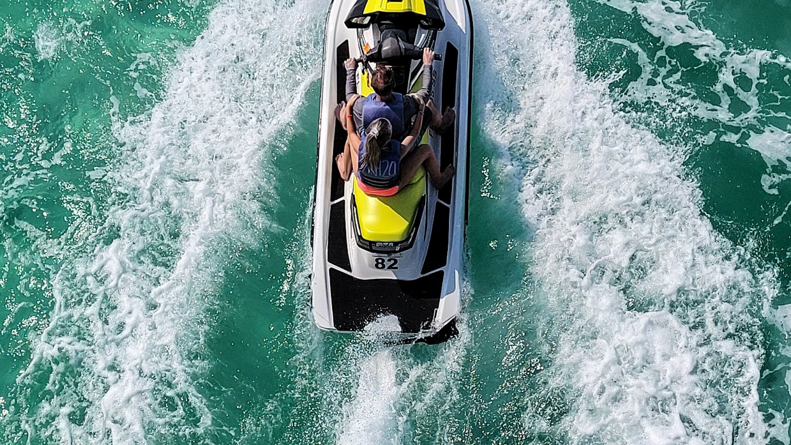 Three friends are riding in a waverunner.