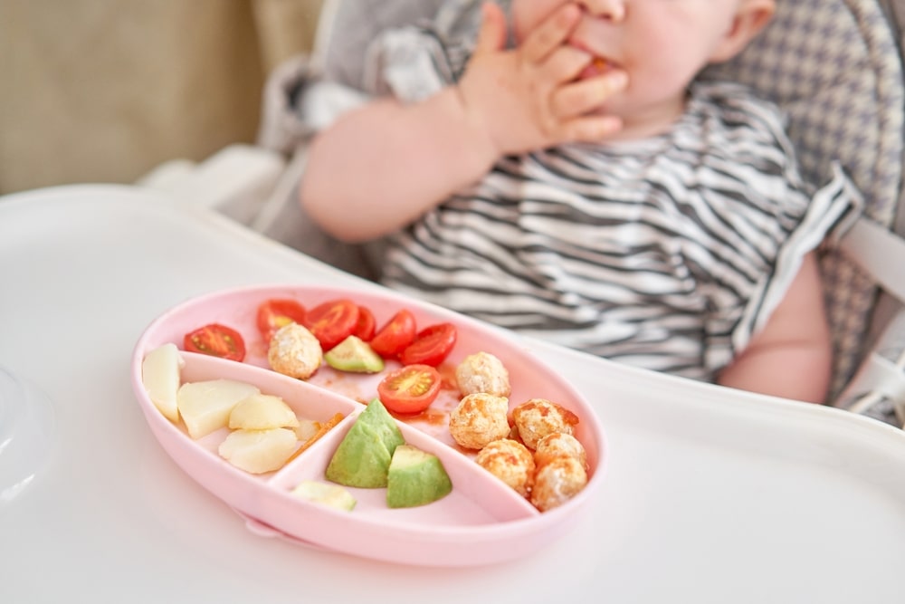 baby eating tomatoes and avacado 