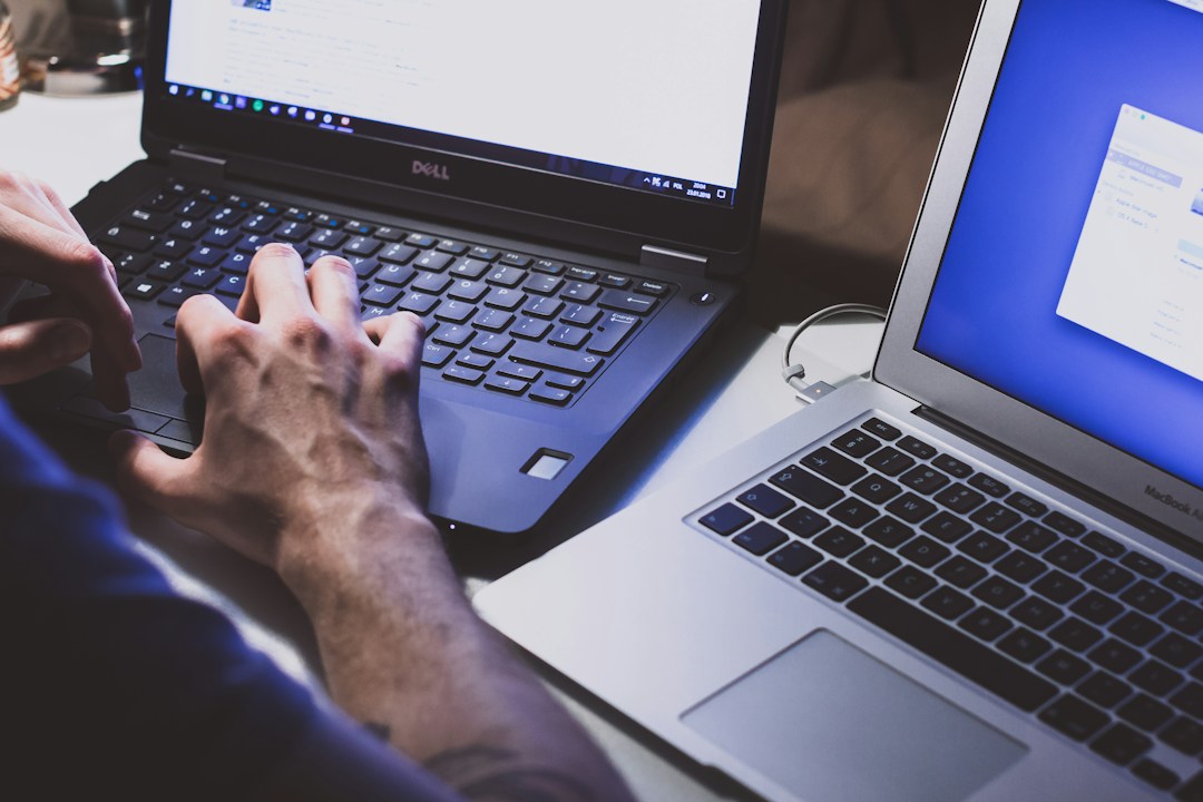 A tech worker implementing Knowledge Management Systems on two laptops