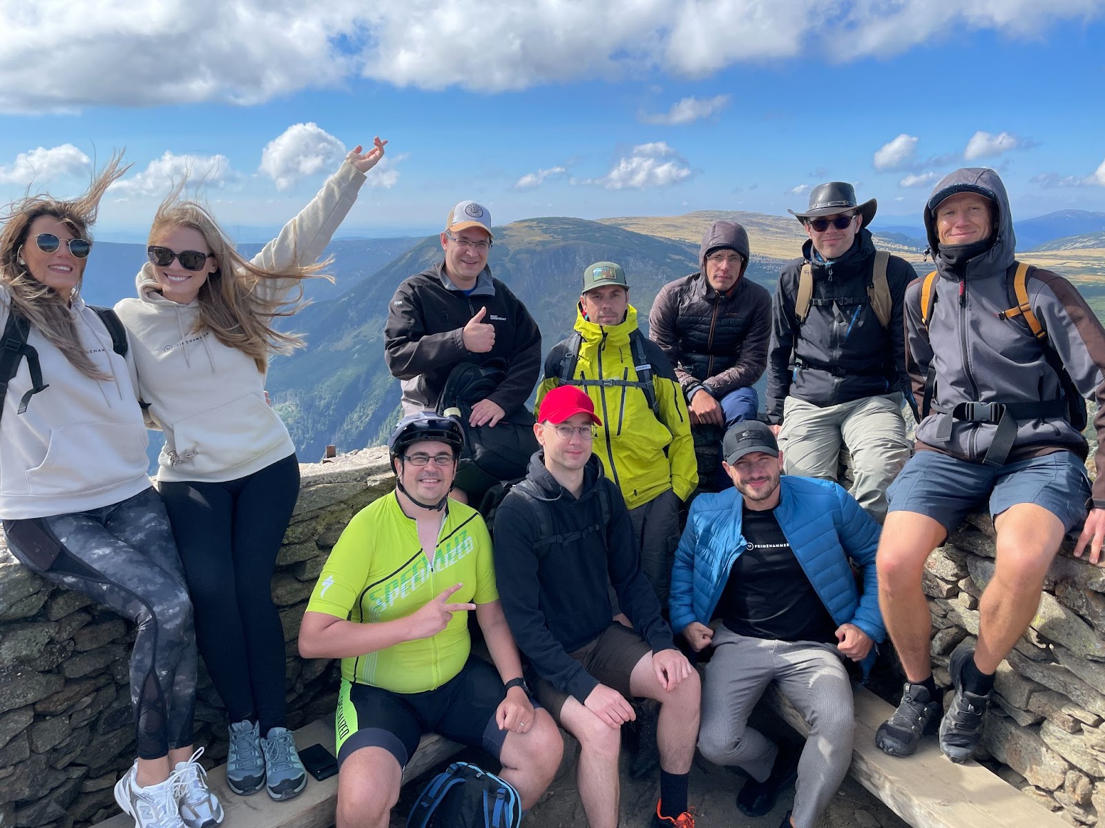 Ten primehammer members pose for a picture after a hike, with the Czech mountains in the background.