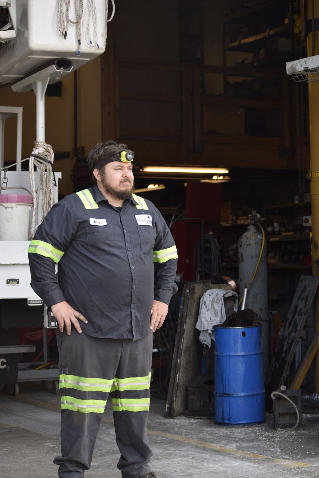 A man standing with his hands on his hips looking out from a repair shop.