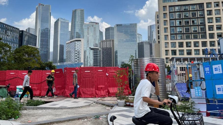 Workers walk past an under-construction area with completed office towers in the background, in Shenzhen's Qianhai new district, Guangdong province, China August 25, 2023.