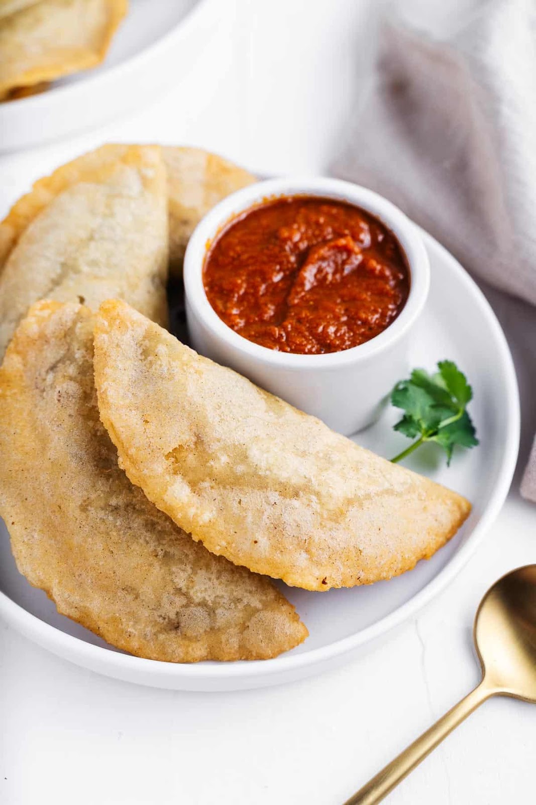 A plate of fried empanadas with dipping sauce.