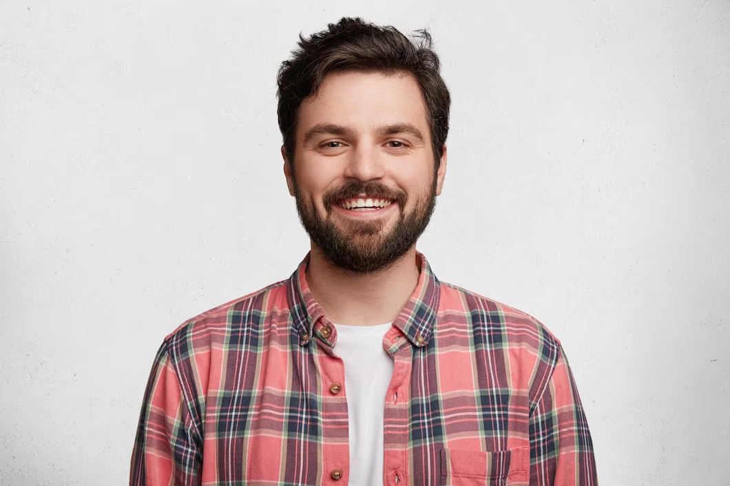 A young bearded man laughing.