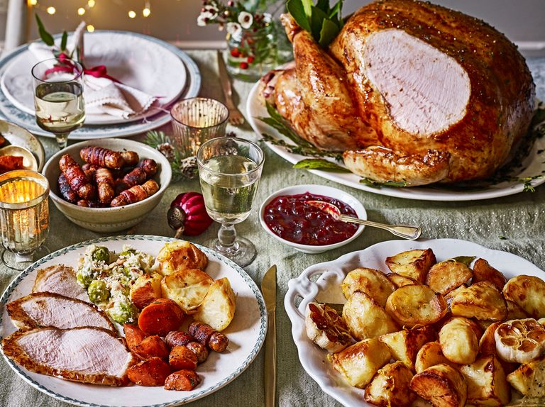 Roast turkey with stuffing, cranberry sauce, mashed potatoes, gravy, roasted vegetables, Christmas pudding, and mince pies