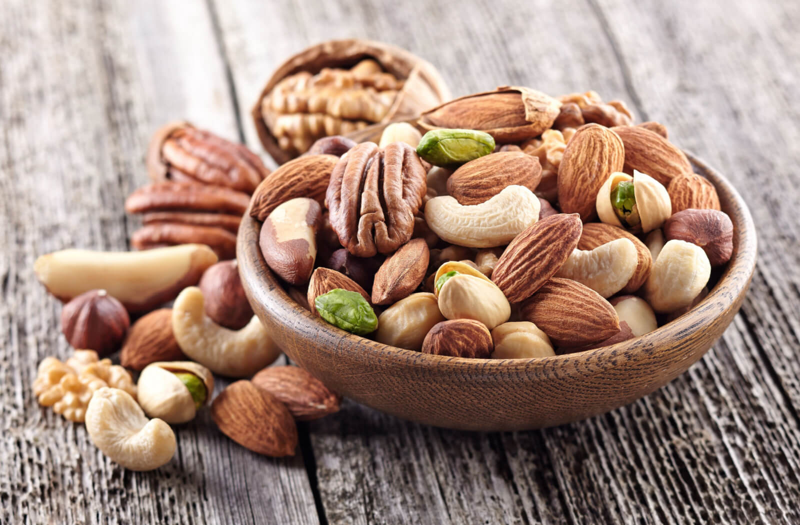A wooden bowl full of assorted nuts.