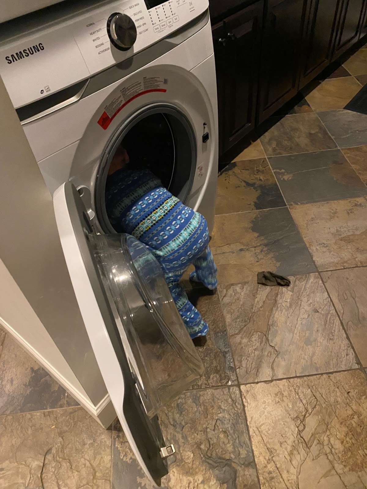 A child climbing into a dryer, illustrating that DIY dryer vent cleaning can cause damage.