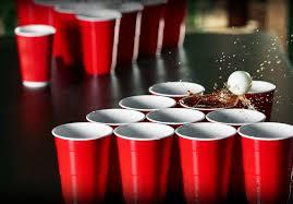 A group of red cups with a white ball in the air

Description automatically generated