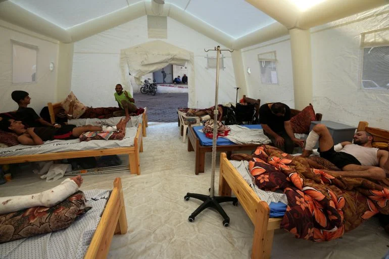 Injured Palestinians sleep in beds set up in a makeshift tent outside a hospital.