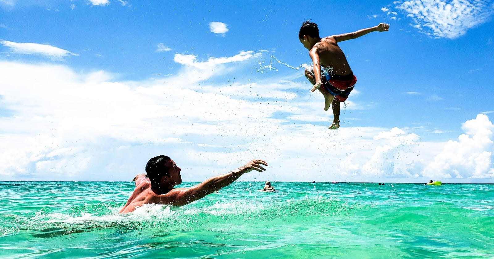  A father and son playing in the ocean together.