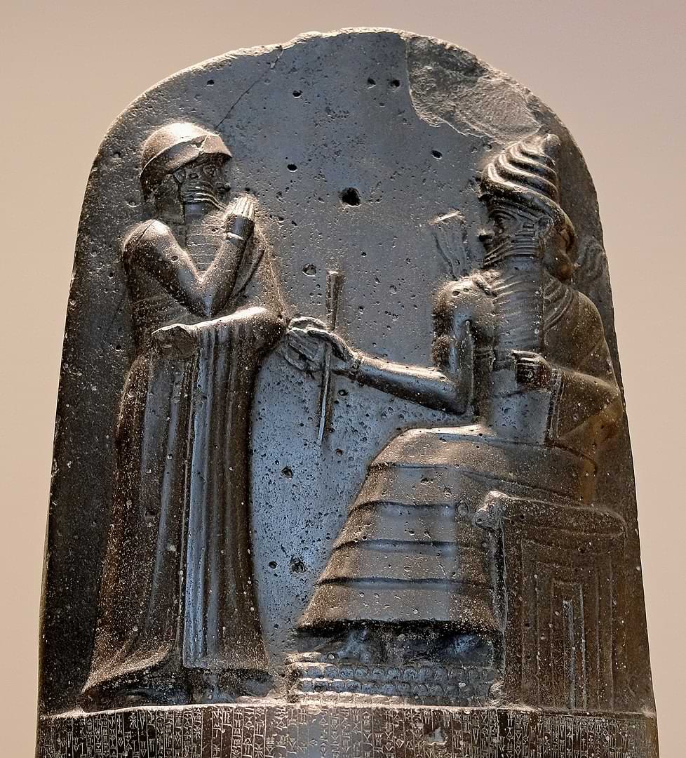 The relief on the Louvre stele of the Code of Hammurabi depicting Hammurabi (standing) receiving his royal insignia from Shamash, the god of justice and light
