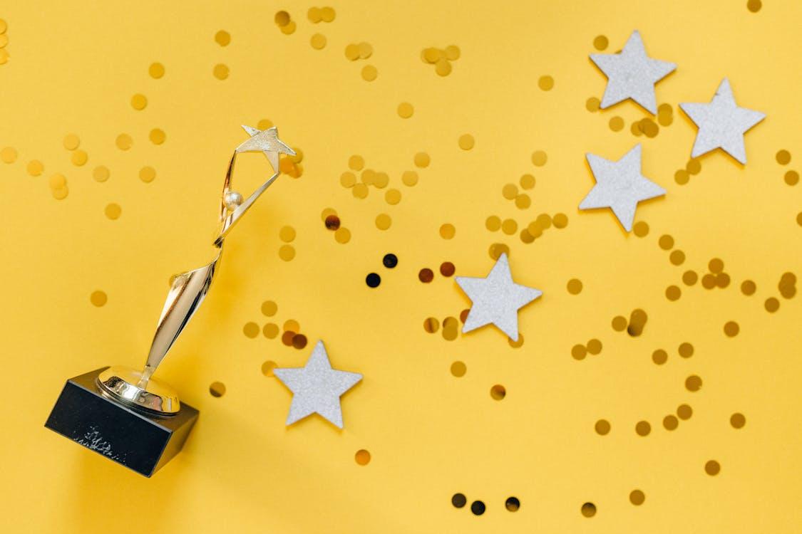 Free Golden Statuette and Stars on Yellow Background Stock Photo