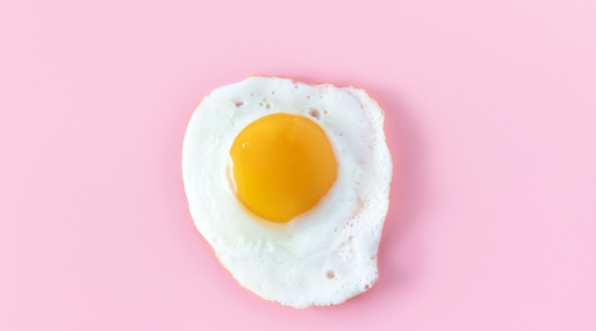 fried egg sunny side up on a pale pink background