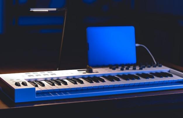 Musical keyboard and tablet in a dark room music production