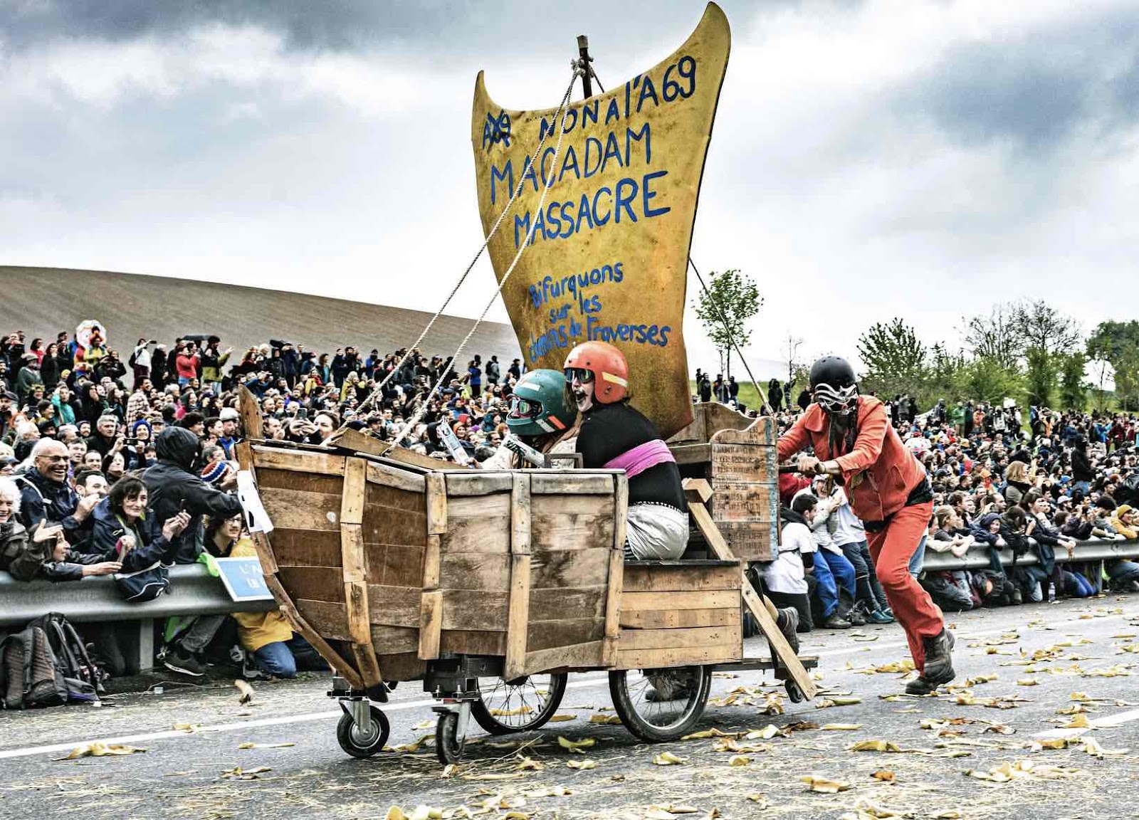 Earth Uprising activists race down a motorway in ship built on bike wheels as a crowd cheers them on