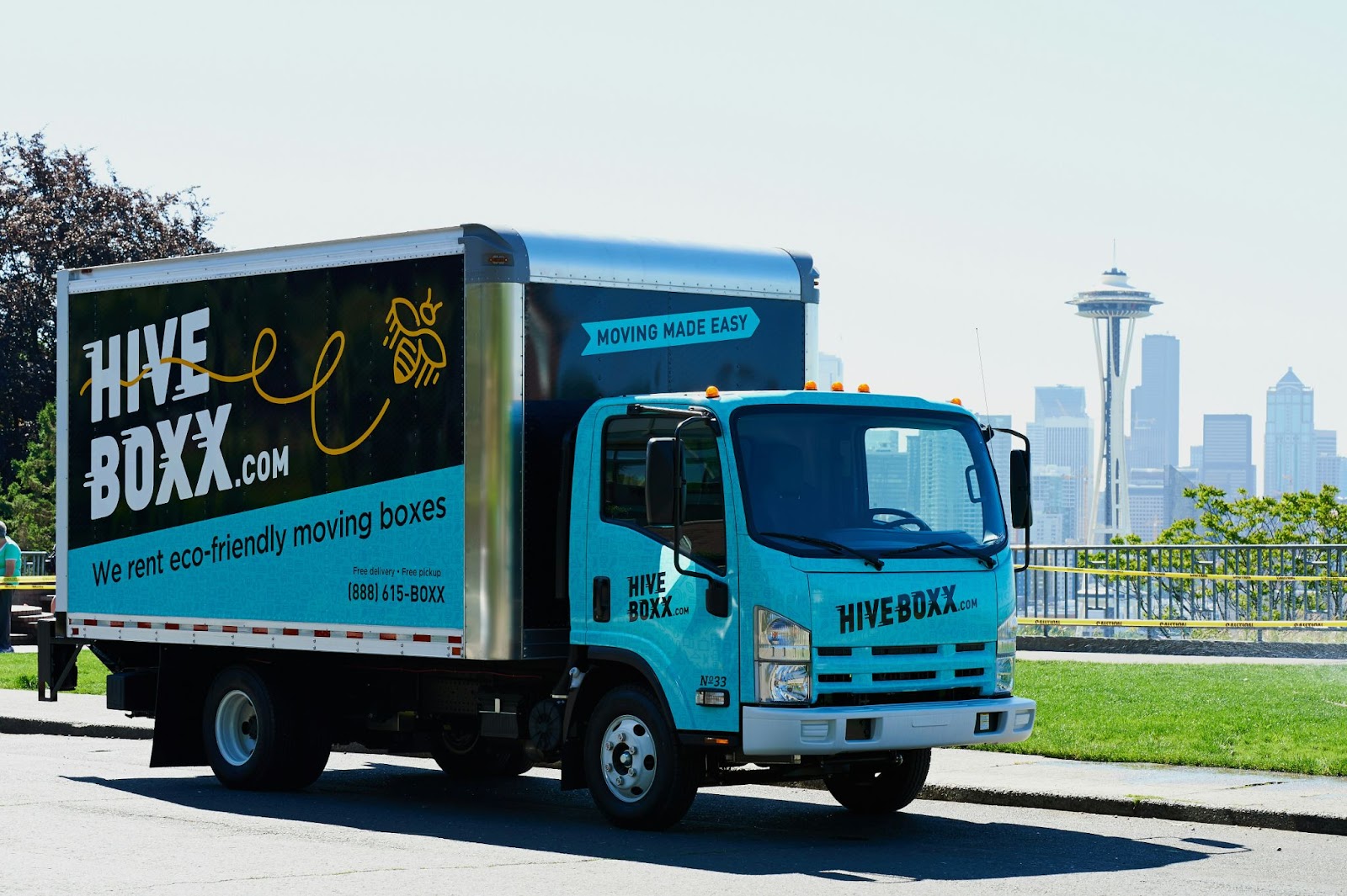 A box truck with blue paneling and advertisements on each panel