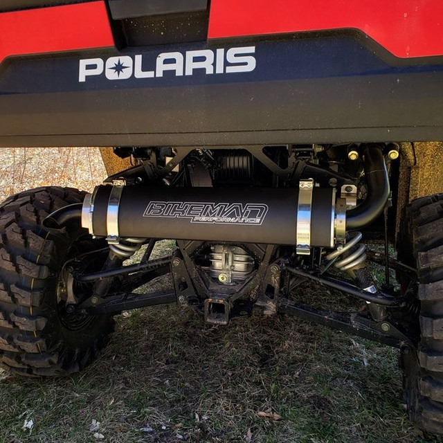An image facing the rear of a Polaris UTV, parked on grass, with a Big MO Slip-On Exhaust installed.