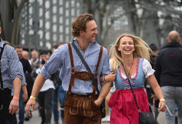 Oktoberfest couple Munich, Germany- 09-27-2022_ A smiling couple in traditional Bavarian attire lock arms as they make their way towards t