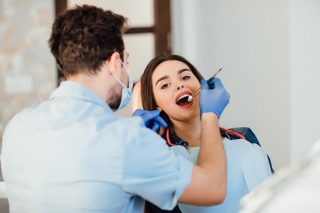 Dentist making professional teeth cleaning withb the cotton, female young patient at the dental office.