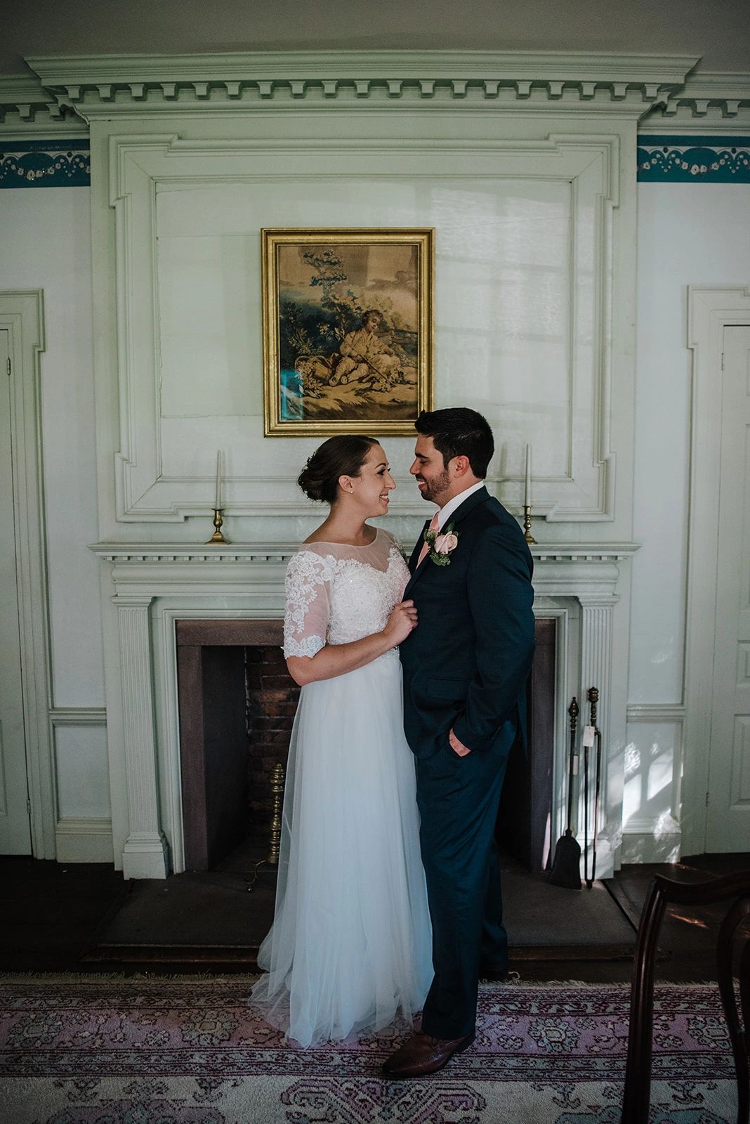 Bride and Groom look at each other and stand in front of fireplace