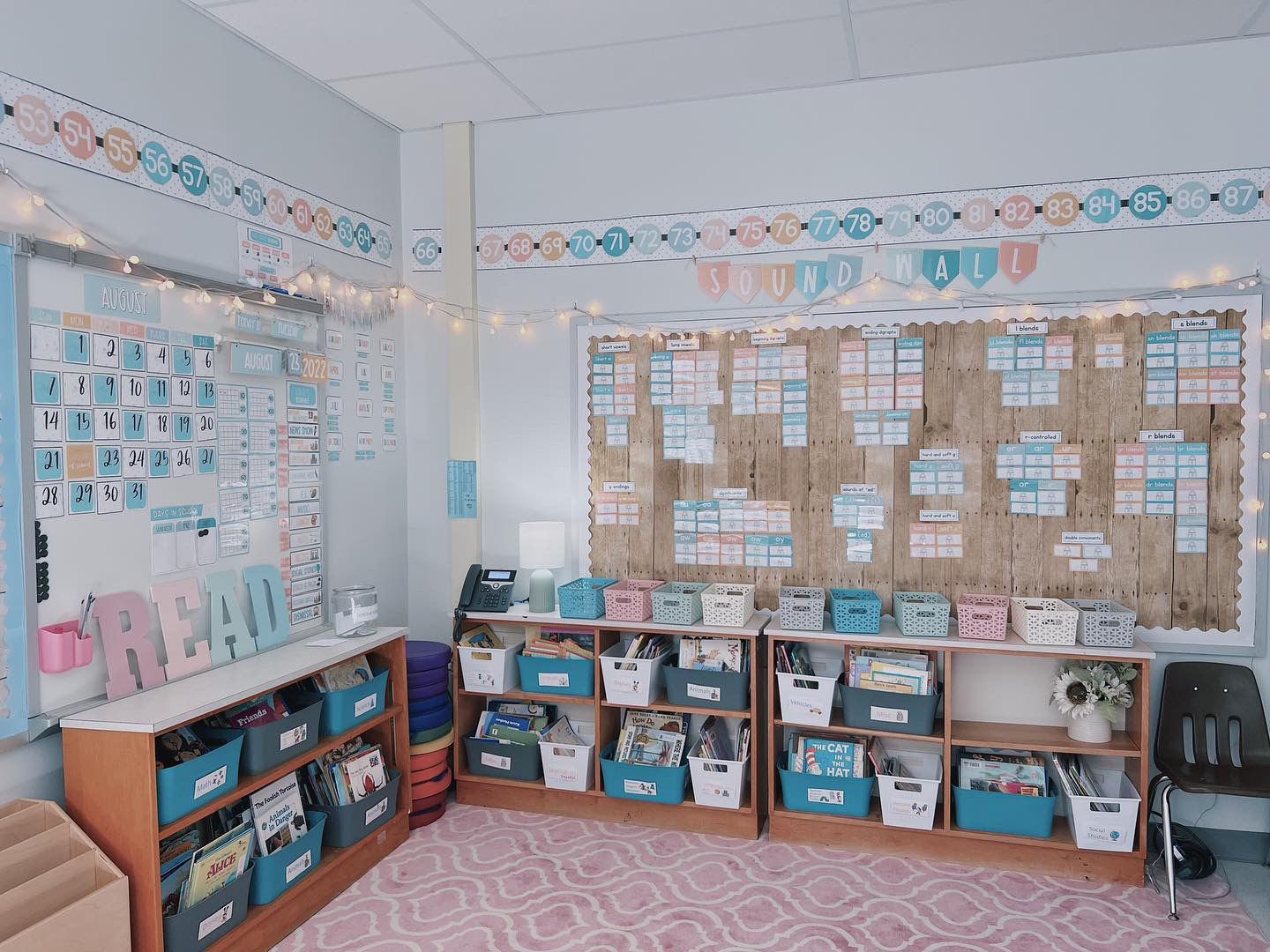 This image shows a reading corner with low bookshelves and books organized in buckets. There are modern calm color decor items all around the classroom. 