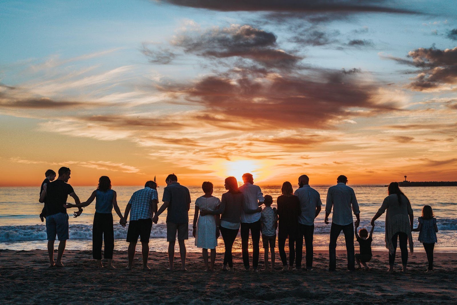 a big family together holding hands at the beach
