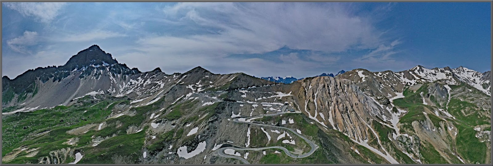 Cycling Col du Galibier from Valloire: panoramic view of roadway snaking up snow-dotted alps