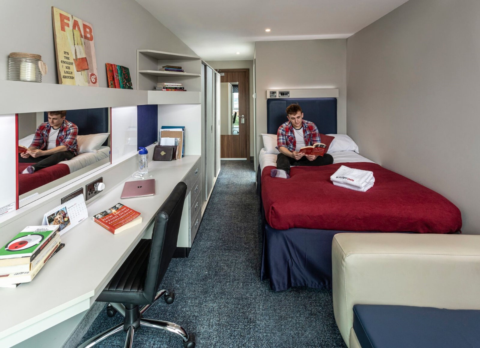 Student reading a book while sitting on his bed in a room at Study Inn.