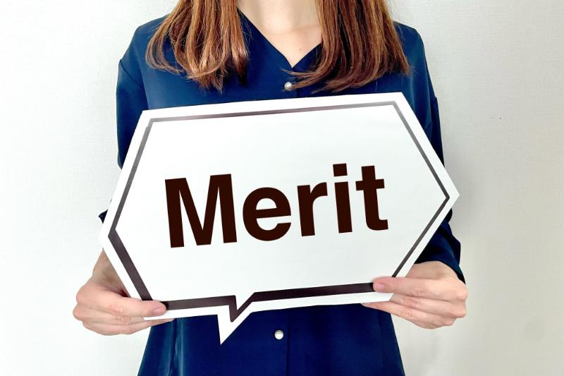 「Merit」と書かれた吹き出し型のパネルを持つ女性