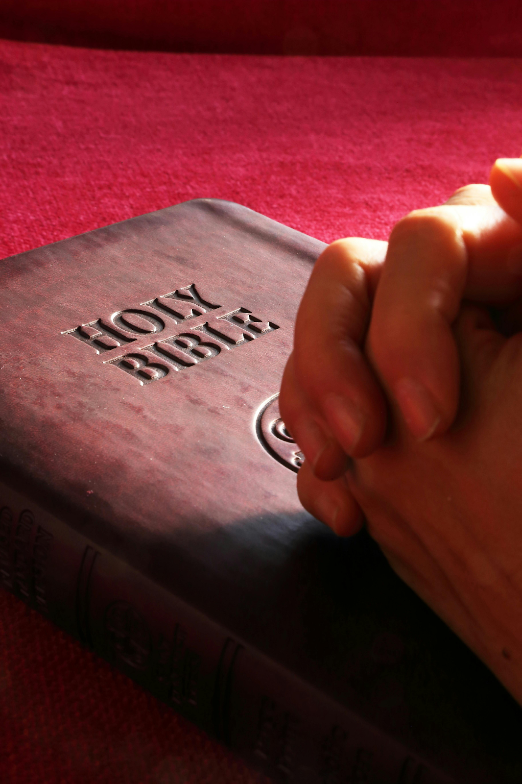 A shot of hands clasped atop the Holy Bible