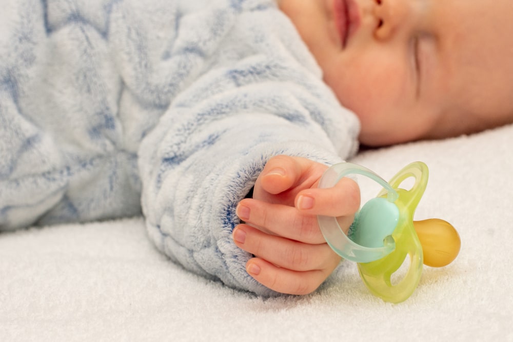 baby sleeping with pacifier in hand 