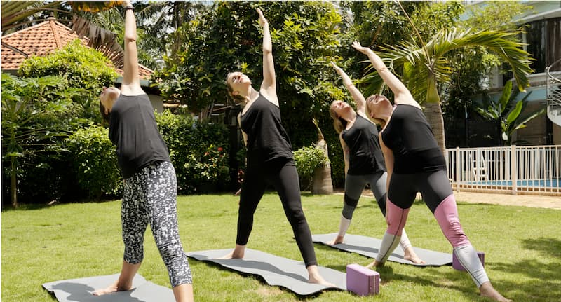 women exercising outdoors in the sun on exercise mats.
