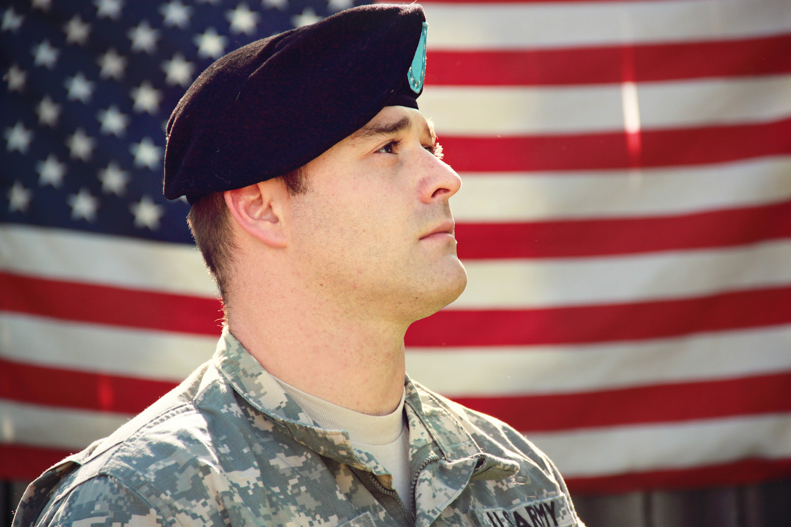 American Soldier is Looking Frontward With the American Flag in The Background 