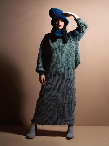 A person in a long sweater and hat

Description automatically generated